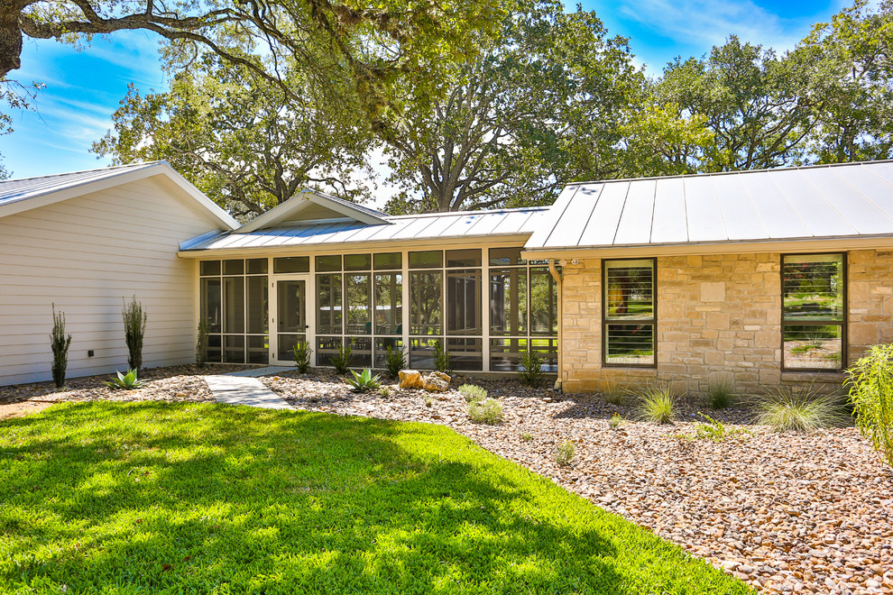 Large 1950s beige one-story mixed siding house exterior photo in Austin with a shed roof and a metal roof