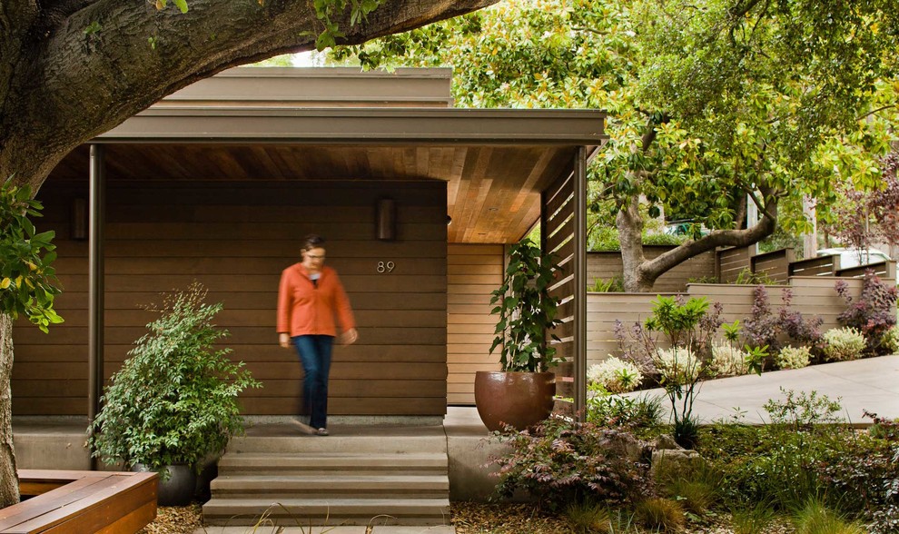 Cette image montre une grande façade de maison marron minimaliste en bois à un étage avec un toit plat.