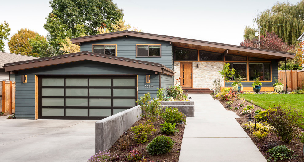 Medium sized and blue midcentury bungalow house exterior in Seattle with stone cladding.