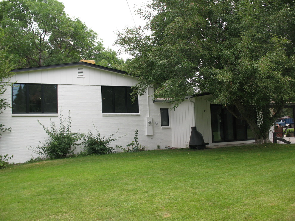 Cette image montre une façade de maison blanche vintage en bois de taille moyenne et à un étage avec un toit à deux pans.