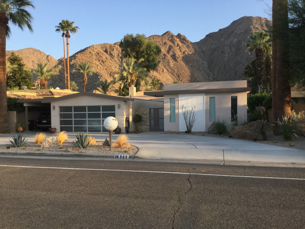 This is an example of a medium sized and beige midcentury bungalow render house exterior in Orange County.