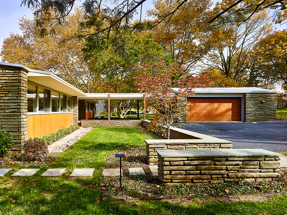 Idée de décoration pour une grande façade de maison multicolore minimaliste en pierre de plain-pied avec un toit à deux pans et un toit végétal.