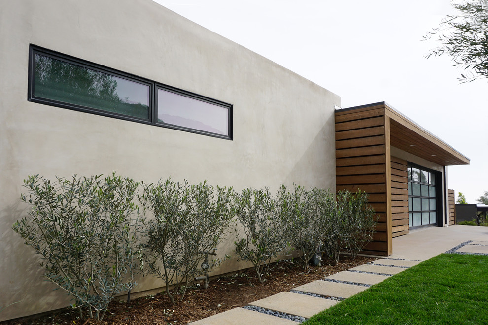 Diseño de fachada de casa gris de tamaño medio de una planta con revestimiento de estuco y tejado plano
