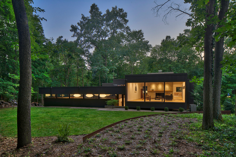 Стильный дизайн: черный частный загородный дом в стиле ретро с плоской крышей - последний тренд