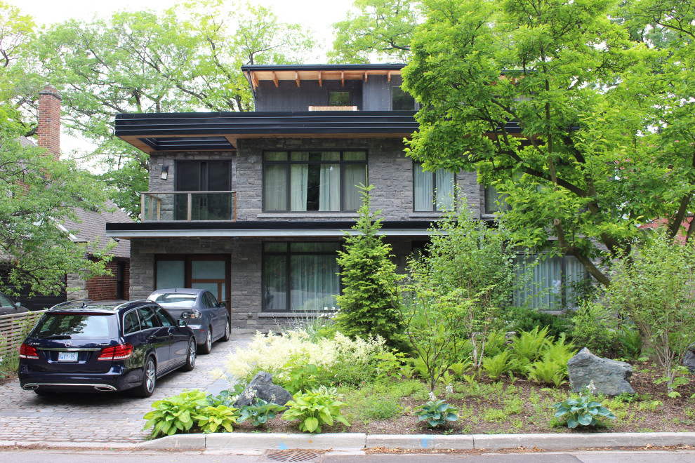 Diseño de fachada de casa gris vintage grande de tres plantas con revestimiento de piedra, tejado plano y techo verde