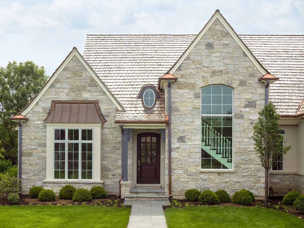 Design ideas for a beige classic two floor house exterior in Chicago with stone cladding and a hip roof.