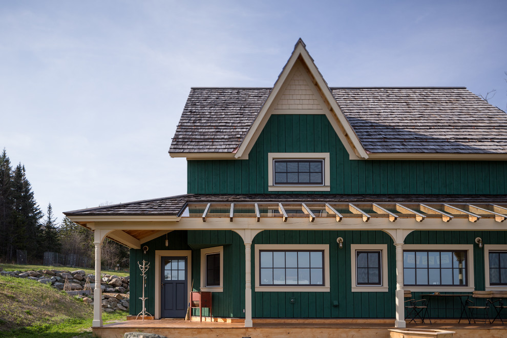 Esempio della facciata di una casa grande verde country a due piani con rivestimento in legno e tetto a capanna