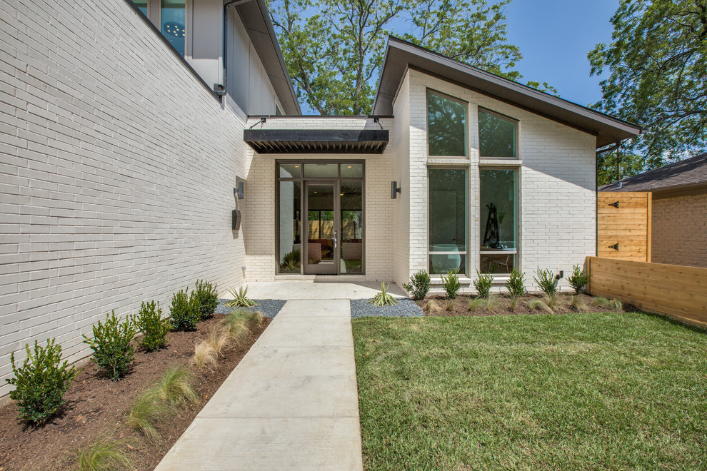 Cette image montre une façade de maison grise minimaliste en brique de taille moyenne et à un étage avec un toit en appentis.