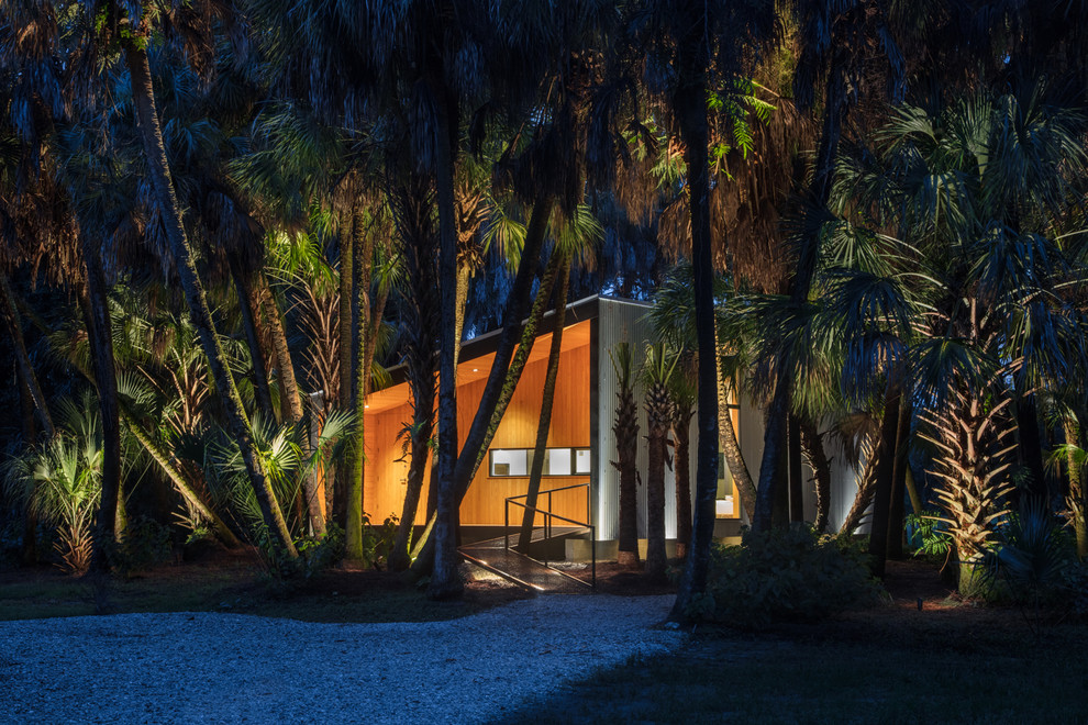 Immagine di un ampio vialetto d'ingresso tropicale esposto a mezz'ombra davanti casa con un ingresso o sentiero, ghiaia e recinzione in legno