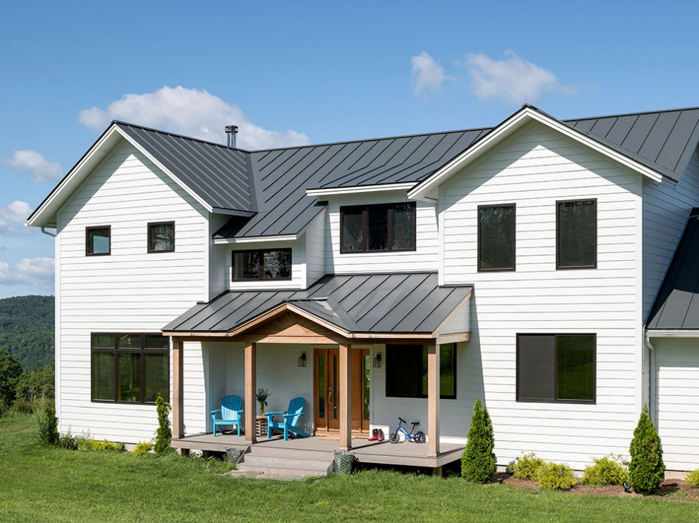 Idée de décoration pour une grande façade de maison blanche champêtre en bois à un étage avec un toit en métal.
