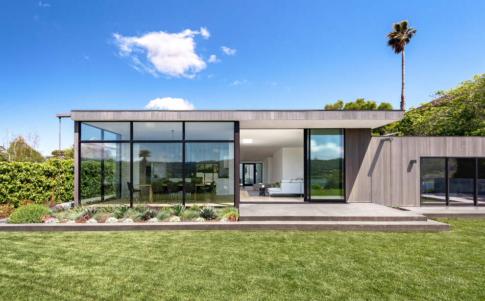 Imagen de fachada de casa gris moderna de tamaño medio con revestimiento de madera, tejado plano y tejado de metal