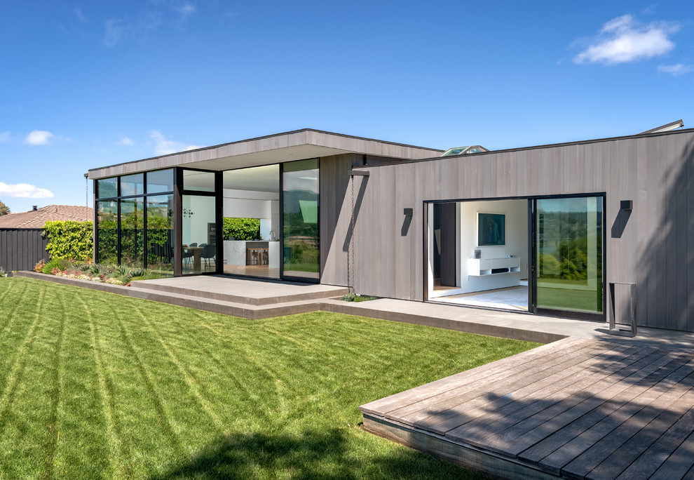 Свежая идея для дизайна: одноэтажный, деревянный, серый частный загородный дом среднего размера в стиле модернизм с плоской крышей и крышей из смешанных материалов - отличное фото интерьера
