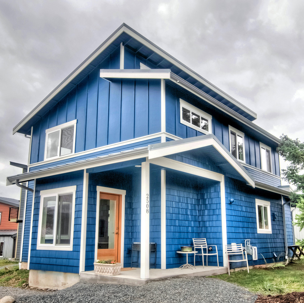 Foto på ett mellanstort funkis blått hus, med två våningar, blandad fasad, pulpettak och tak i metall