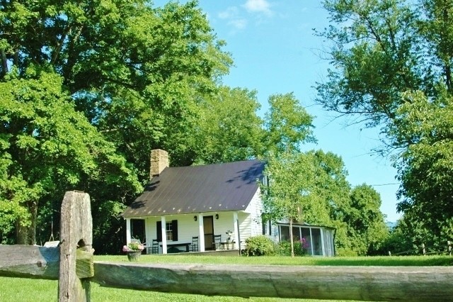 Bild på ett litet rustikt vitt trähus, med tre eller fler plan
