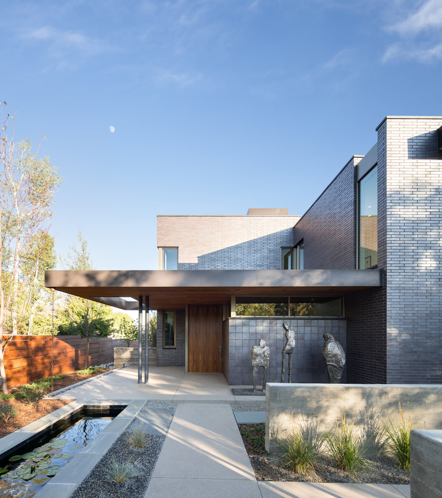 Diseño de fachada negra minimalista de dos plantas con revestimiento de ladrillo y tejado plano