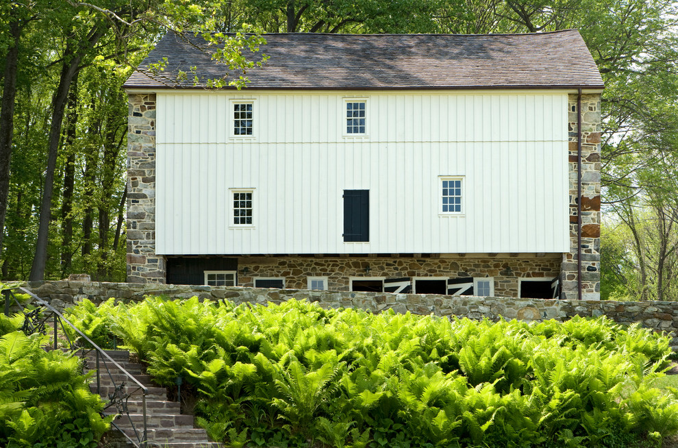 This is an example of a large and white country house exterior in Philadelphia with three floors, wood cladding and a pitched roof.