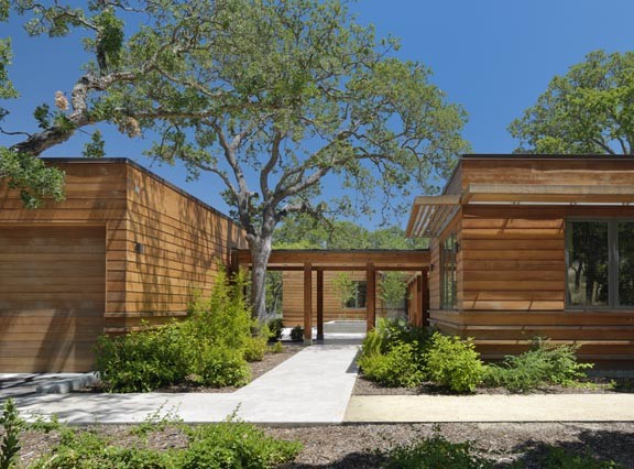 На фото: большой, одноэтажный, коричневый, деревянный частный загородный дом в стиле модернизм с плоской крышей с