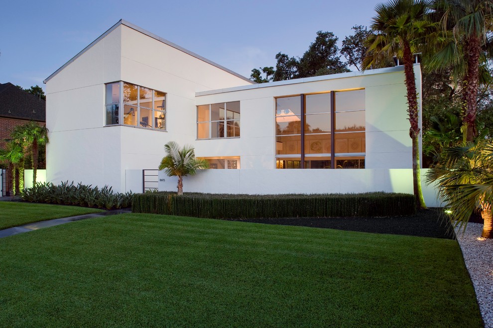 Стильный дизайн: маленький, двухэтажный, белый дом в стиле модернизм с облицовкой из цементной штукатурки и плоской крышей для на участке и в саду - последний тренд