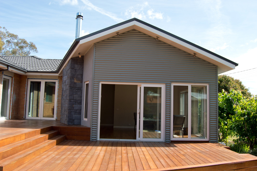 На фото: одноэтажный, серый дом среднего размера в современном стиле с облицовкой из металла и двускатной крышей