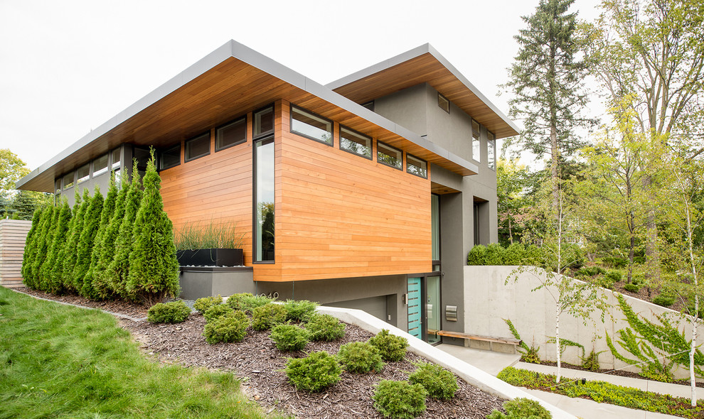 Diseño de fachada gris minimalista de dos plantas con revestimiento de madera