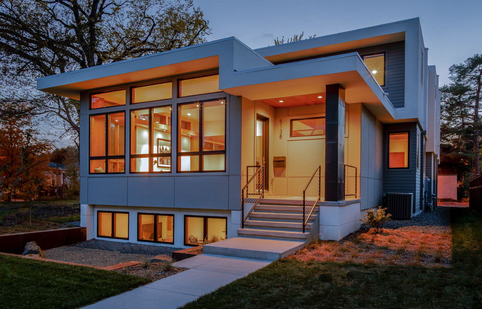 Aménagement d'une grande façade de maison grise moderne à un étage avec un revêtement mixte et un toit plat.