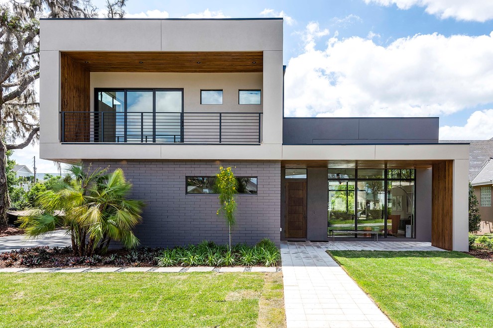 Idées déco pour une grande façade de maison beige contemporaine à niveaux décalés avec un revêtement mixte et un toit plat.