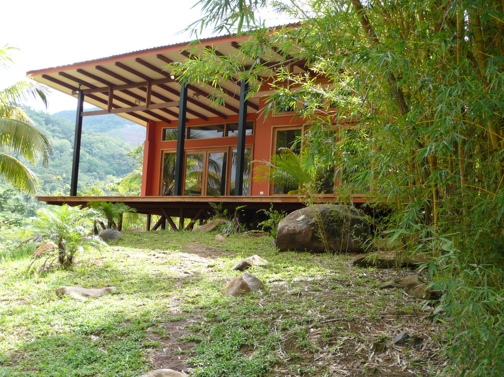 This is an example of a medium sized and red world-inspired bungalow concrete house exterior in Seattle with a lean-to roof and a metal roof.