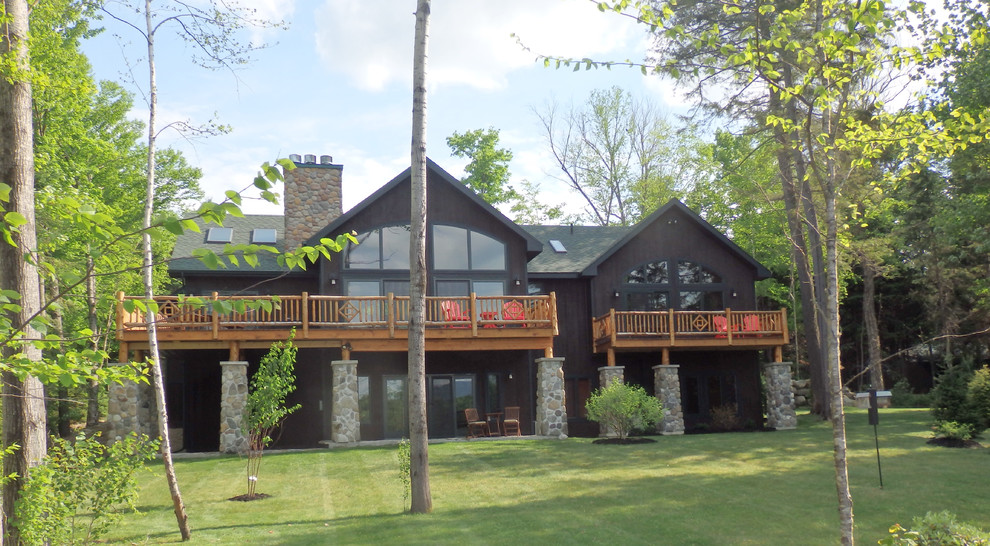 Exemple d'une grande façade de maison marron montagne en bois à un étage avec un toit à quatre pans.