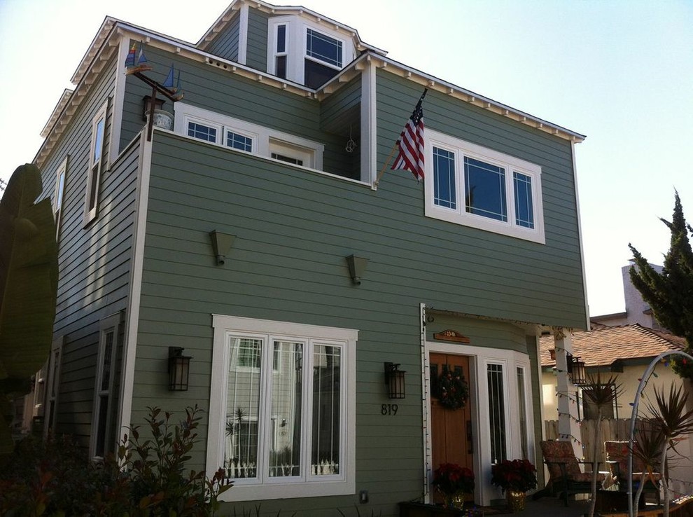 Ejemplo de fachada verde costera de tamaño medio de tres plantas con revestimiento de vinilo y tejado plano