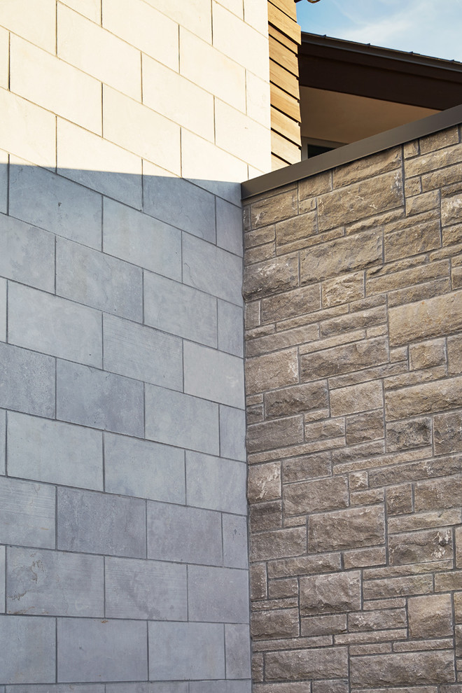 Réalisation d'une grande façade de maison marron minimaliste en pierre à un étage avec un toit à quatre pans.