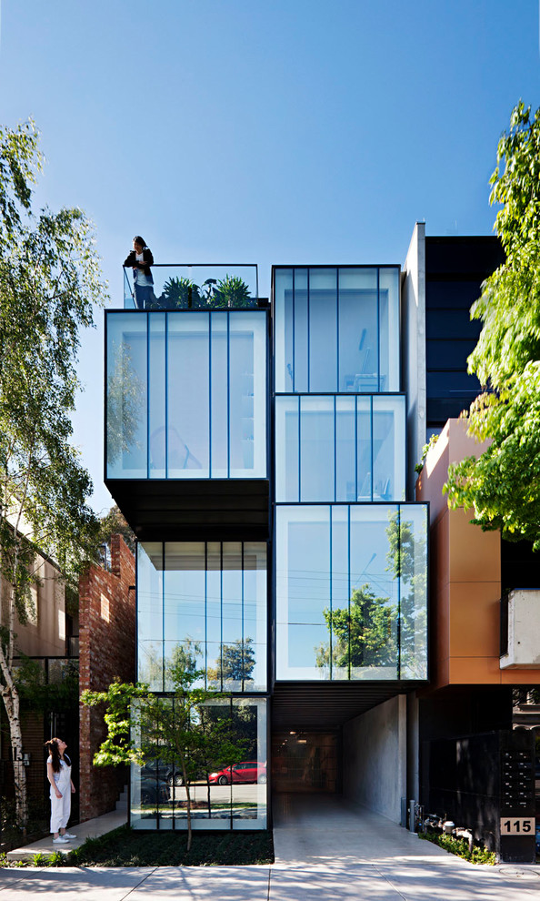 Diseño de fachada de casa actual de tres plantas con revestimiento de vidrio y tejado plano