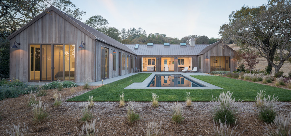 Idee per la villa grande marrone country a un piano con rivestimento in legno, tetto a capanna e copertura in metallo o lamiera