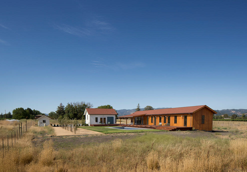Cette image montre une façade de maison marron rustique de taille moyenne et de plain-pied avec un revêtement mixte, un toit à deux pans et un toit en shingle.