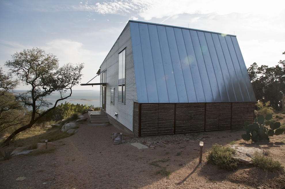 Réalisation d'une petite façade de maison grise design de plain-pied avec un revêtement mixte et un toit en appentis.
