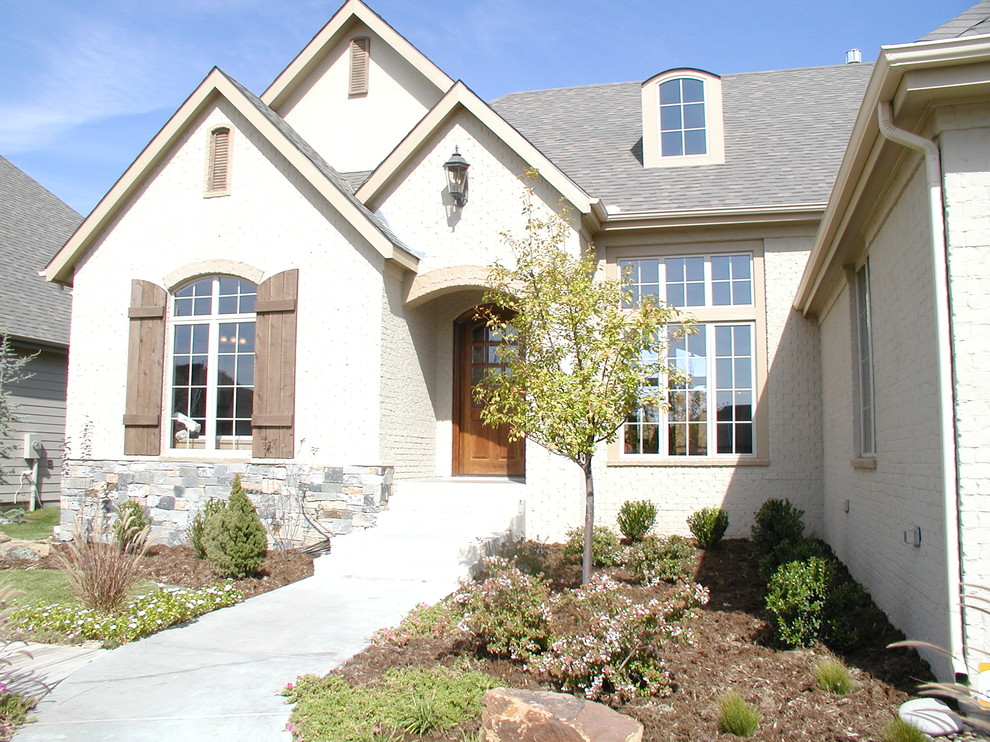 Immagine della facciata di una casa bianca classica a un piano di medie dimensioni con rivestimento in mattoni, tetto a mansarda e abbinamento di colori