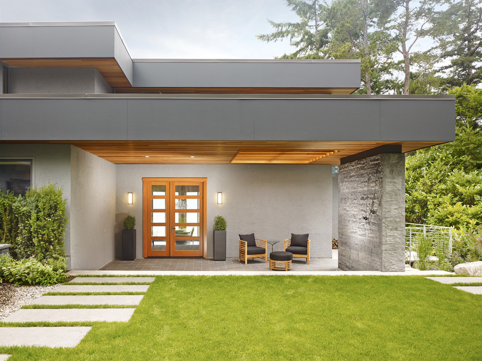 Ejemplo de fachada gris moderna de tamaño medio de dos plantas con revestimiento de estuco y tejado plano