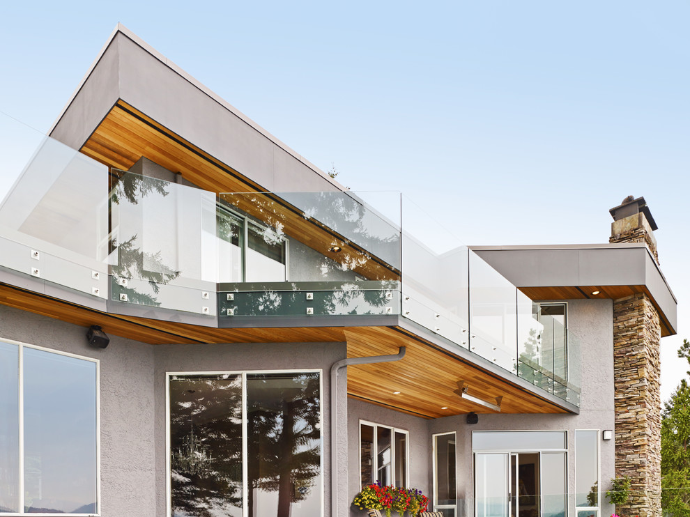 Ispirazione per la facciata di una casa grigia moderna a due piani di medie dimensioni con rivestimento in stucco e tetto piano