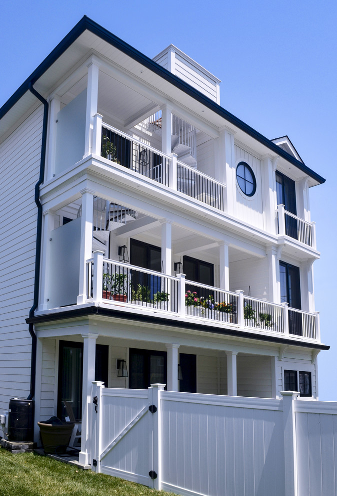 This is an example of a large and white beach style detached house in Other with vinyl cladding and three floors.