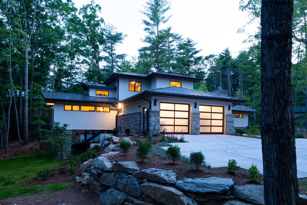 Idées déco pour une façade de maison beige moderne en stuc de taille moyenne et à un étage avec un toit à quatre pans et un toit en métal.