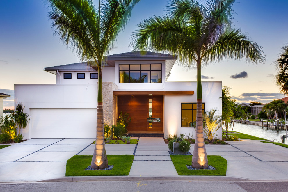 На фото: двухэтажный, белый дом в морском стиле с облицовкой из цементной штукатурки и вальмовой крышей с