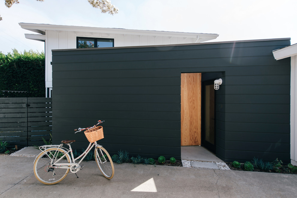 Ejemplo de fachada de casa negra minimalista pequeña de dos plantas con revestimiento de aglomerado de cemento, tejado plano y tejado de varios materiales