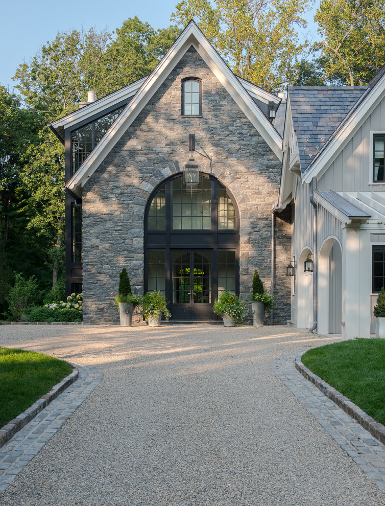 На фото: трехэтажный, серый, большой частный загородный дом в стиле неоклассика (современная классика) с облицовкой из камня, двускатной крышей и крышей из гибкой черепицы