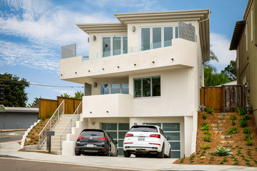 Immagine della facciata di una casa grande beige contemporanea a tre piani con rivestimento in stucco e copertura a scandole