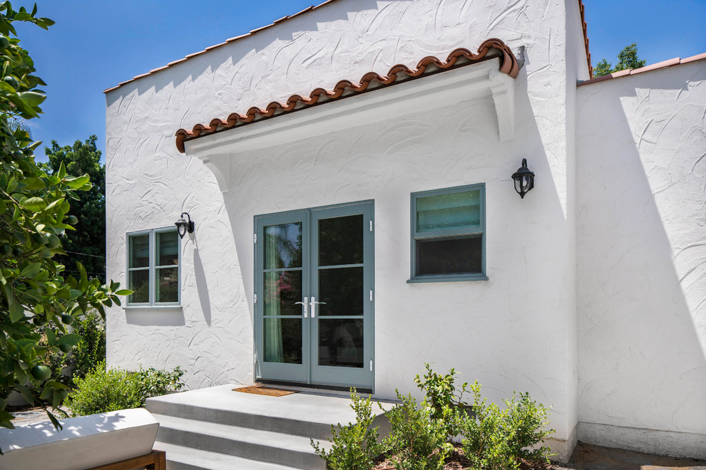 Imagen de fachada de casa blanca clásica renovada de tamaño medio de una planta con revestimiento de estuco, tejado plano y tejado de varios materiales