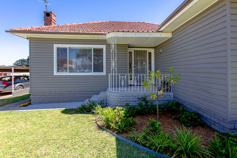Mid-sized mid-century modern gray wood and clapboard house exterior photo in Sydney with a hip roof, a tile roof and a red roof