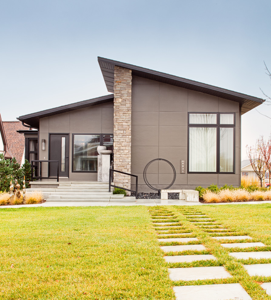 Cette photo montre une façade de maison grise tendance en béton de taille moyenne et de plain-pied avec un toit en appentis.
