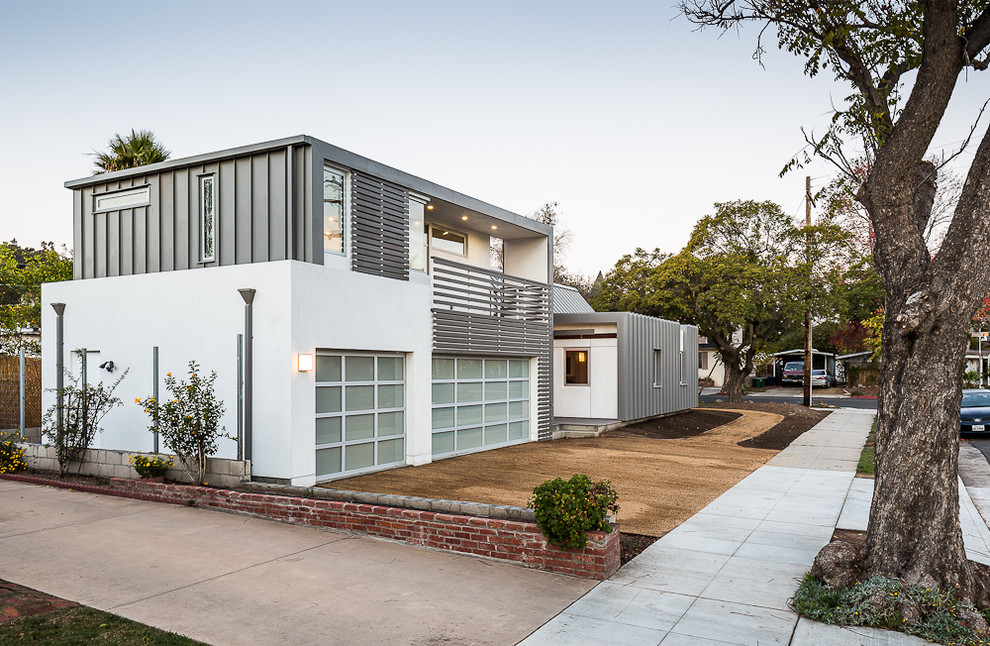 Diseño de fachada de casa blanca minimalista grande a niveles con revestimiento de estuco y tejado a cuatro aguas