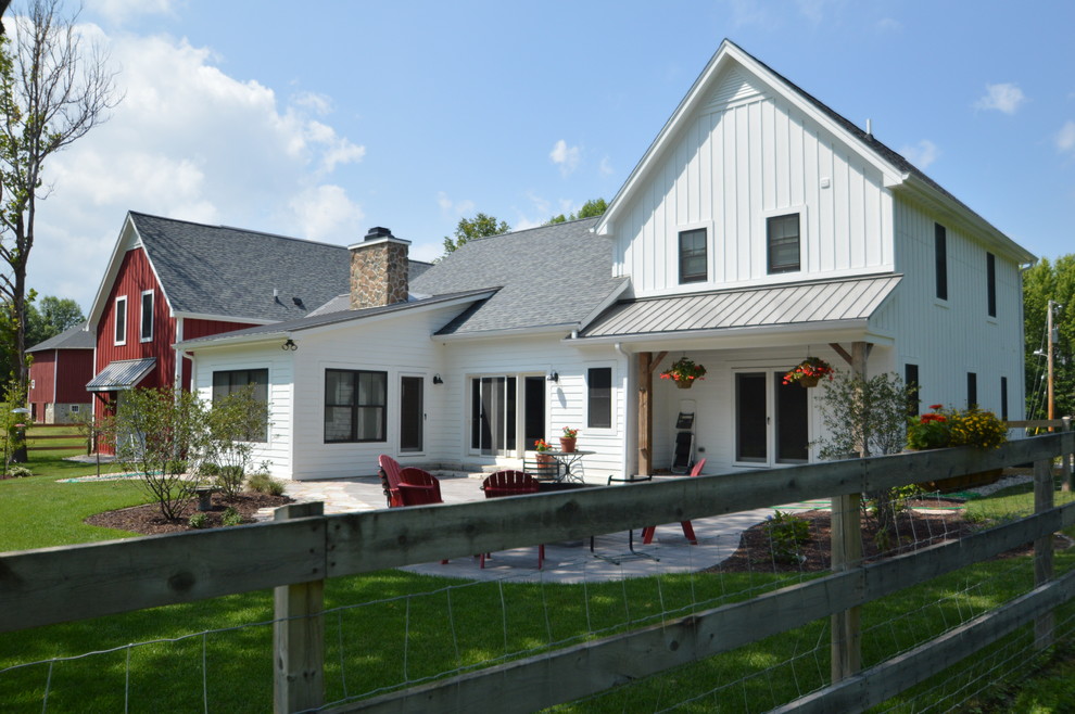 Aménagement d'une grande façade de maison blanche campagne en bois et planches et couvre-joints de plain-pied avec un toit à deux pans et un toit mixte.