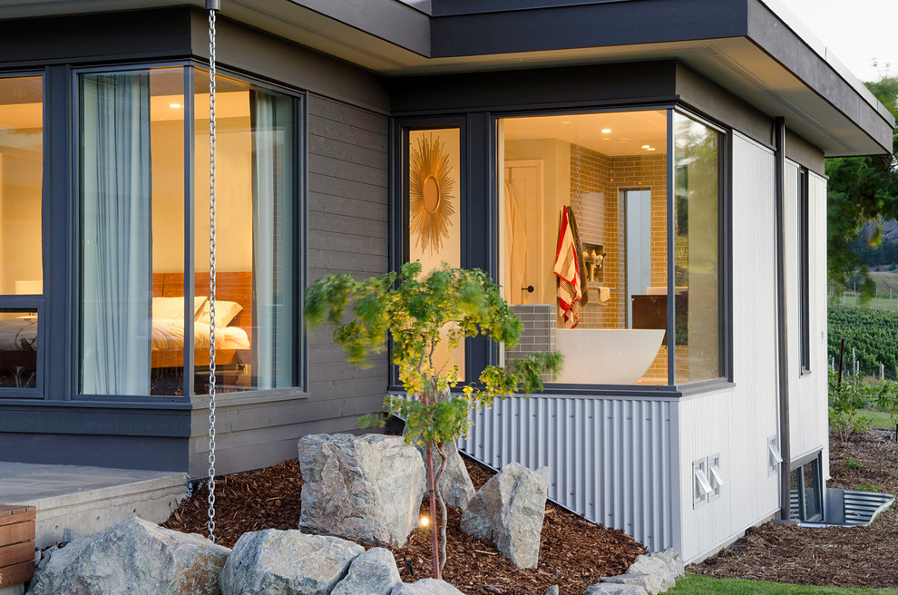 Diseño de fachada de casa gris moderna de tamaño medio de una planta con revestimientos combinados, tejado plano y tejado de metal