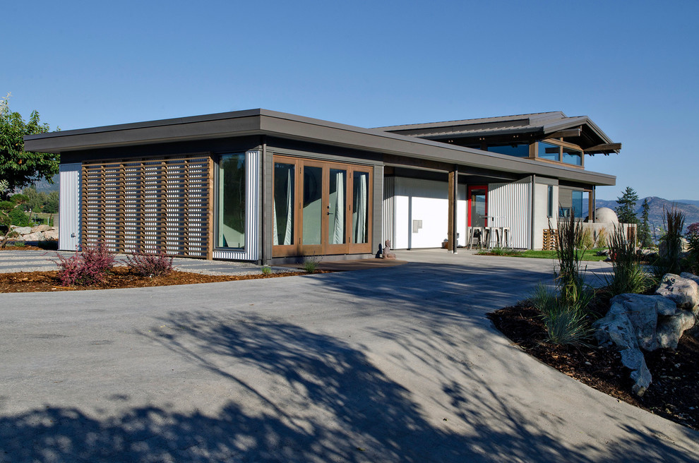 Идея дизайна: одноэтажный, деревянный, серый частный загородный дом среднего размера в стиле модернизм с плоской крышей и металлической крышей